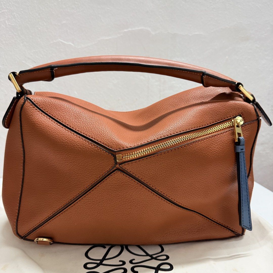 Loewe Puzzle Bag Tan Leather (Category: Luxury Bags & Wallets) located in Santa Rosa. Submitted by secillanomaelisa (Listing ID 1450306937, Image 2). Description: - Loewe Puzzle Bag - Crafted from premium pebbled leather - Elegant gold hardware details - Secure zipper closure with a distinctive blue leather pull tab - Comfortable top handle for easy carrying - Spacious interior, ideal for everyday essentials - A versatile and stylish everyday com