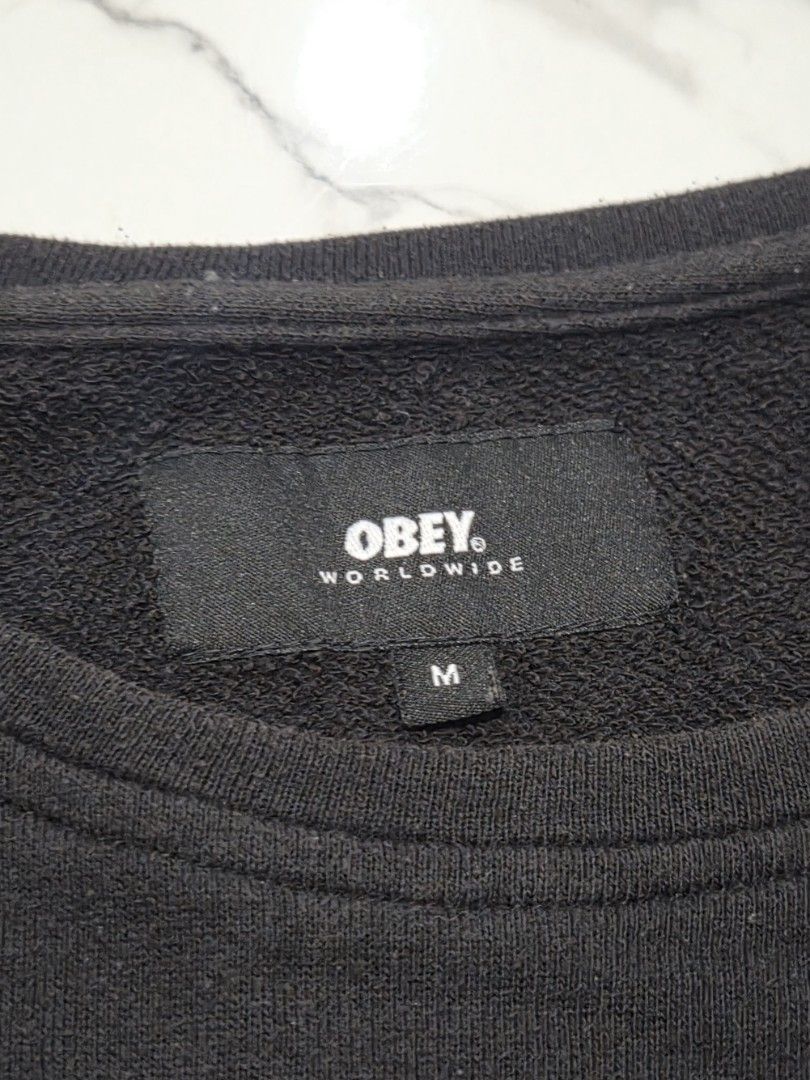 OBEY Worldwide Black Sweatshirt (Category: Coats, Jackets and Outerwear) located in Manila. Submitted by weirdlysa (Listing ID 1450199325, Image 2). Description: - OBEY sweatshirt - black color - men's size M - baggy, oversized fit - plain design with small "obey worldwide propaganda" patch in front.