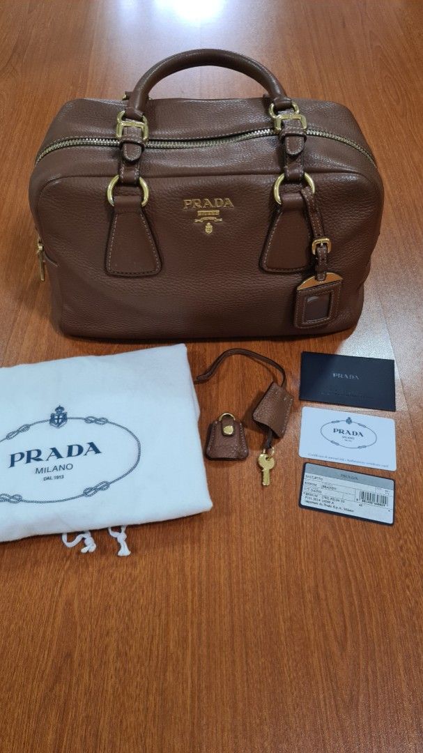 Prada Brown Leather Satchel Bag with Lock and Key (Category: Luxury Bags & Wallets) located in Manila. Submitted by lc_declut (Listing ID 1450148839, Image 1). Description: - Genuine brown pebbled leather Prada satchel - Elegant gold hardware details - Includes original dust bag, authenticity cards, lock, and key - Interior features a zippered pocket and a slip pocket - Protective feet on the bottom for durability - Ideal for everyday use.