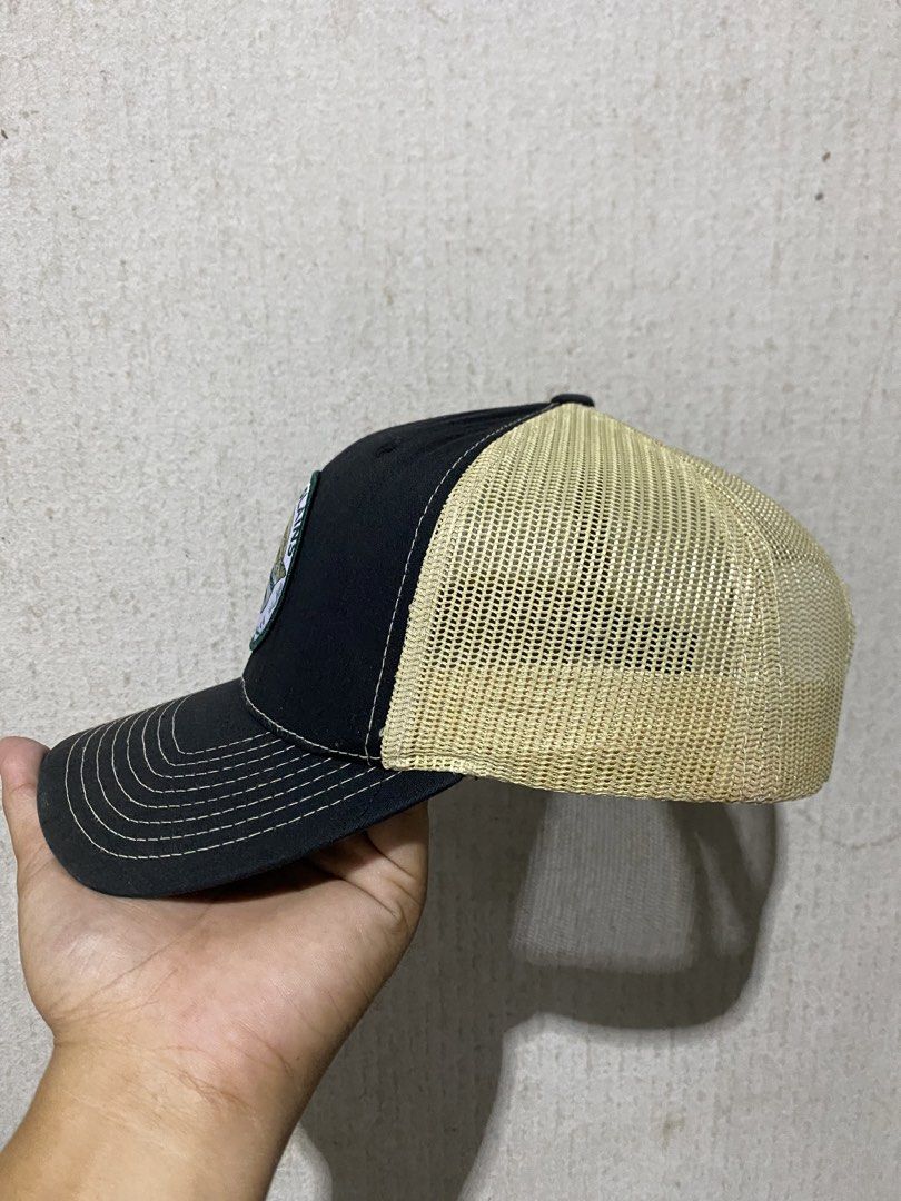 Richardson Peak to Plains Guide Service Trucker Hat (Category: Caps & Hats) located in Puerto Princesa. Submitted by earlpogitrhift (Listing ID 1450289910, Image 3). Description: - Black and tan trucker hat - Features a circular patch with 'Peak to Plains Guide Service' text and mountain graphic - Richardson brand with adjustable strap - Mesh back for breathability - Ideal for outdoor adventures.