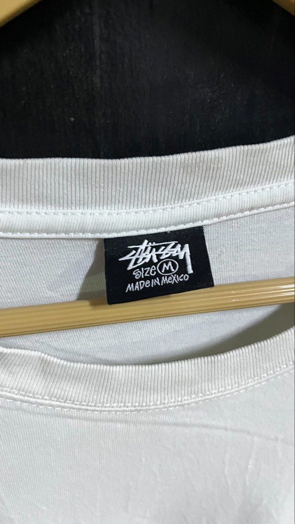 Stussy Graphic Tee T-Shirt Size M (Category: Tshirts & Polo Shirts ) located in Pontevedra. Submitted by thrift01 (Listing ID 1450138549, Image 2). Description: - Classic white Stussy graphic t-shirt - Features a prominent red 'S' logo and text on the front - "Made in Mexico" label - Crafted from 100% cotton for comfort - Easy care: Machine wash cold, tumble dry low - Ideal for casual outfits and streetwear looks.