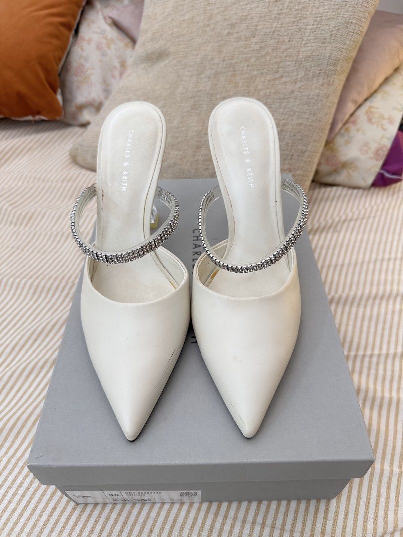 Charles & Keith White Mules with Rhinestone Strap and Clear Heel (Category: Heels) located in Kuala Lumpur. Submitted by ntsharusli (Listing ID 1450424139, Image 1). Description: - Brand: Charles & Keith - Style: White pointed-toe mules - Size: 38 - Features: Sparkly rhinestone strap, clear sculpted heel - Closure: Slip-on - Condition: Comes with original box.