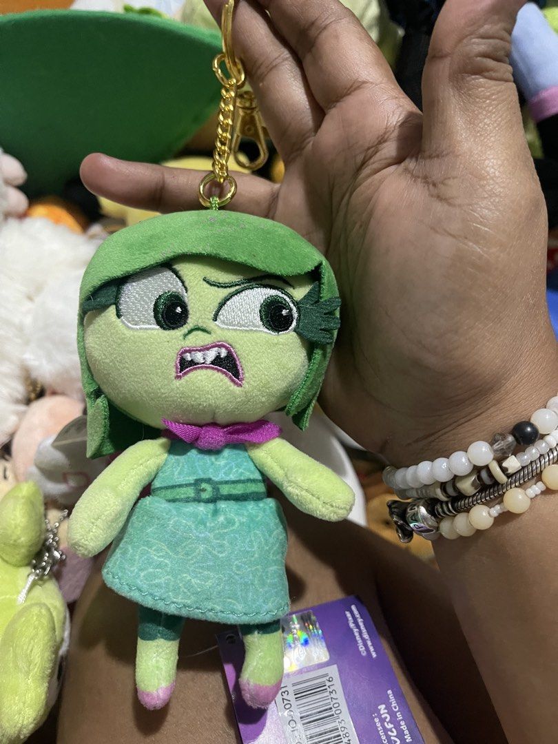 Disney Pixar Inside Out 2 Disgust Plush Keychain (Category: Plushies & Soft Toys) located in Muntinlupa City. Submitted by joanofarc1013 (Listing ID 1450347088, Image 1). Description: - Adorable Disgust plush keychain from Disney/Pixar's Inside Out 2. - Features a shiny gold-colored keyring. - Brand new with tag still attached. - Approximately 4-5 inches in height. - Ideal accessory for backpacks, purses, or bags..