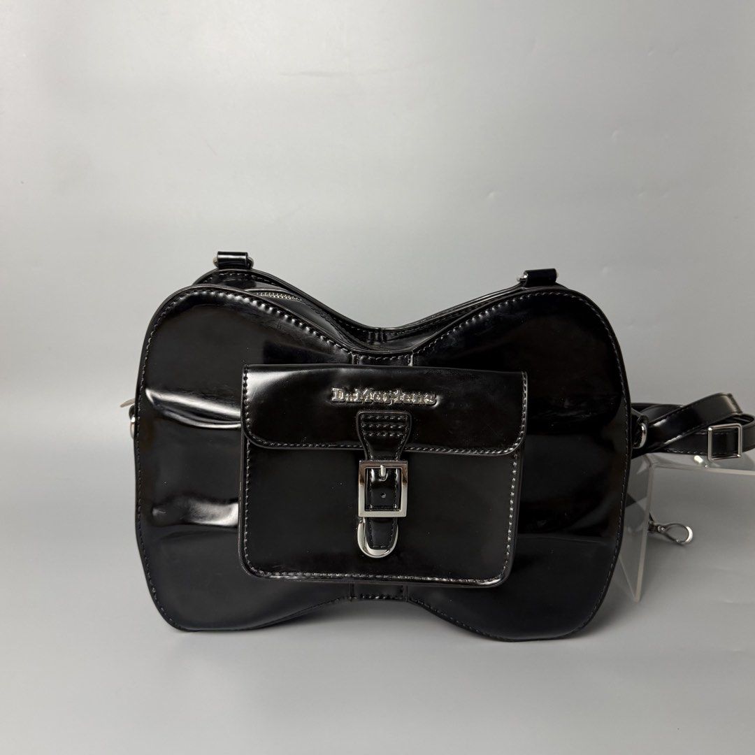 Dr. Martens Patent Leather Saddle Bag Black (Category: Luxury Bags & Wallets) located in Malasiqui. Submitted by fosh0fosh0 (Listing ID 1450341217, Image 1). Description: - Brand: Dr. Martens - Material: Black patent leather - Style: Unique saddle bag shape - Features: Eye-catching design, buckle closure front pocket, zip main compartment, adjustable strap - Finish: Shiny - Versatile: Great for everyday use or nights out.