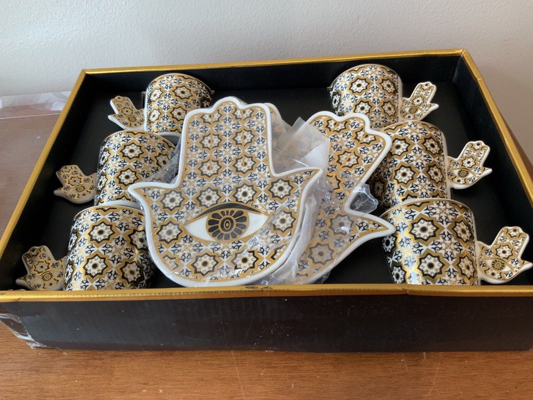 Hamsa Hand Evil Eye Coffee Cup and Saucer Set (Category: Coffee & Tea Tableware) located in Makati City. Submitted by nfb1234 (Listing ID 1450347256, Image 1). Description: - Set of 6 coffee cups and saucers - Features a Hamsa hand design with an evil eye in the center - Detailed gold and black pattern on cups and saucers - Comes in a beautiful presentation box - Ideal for serving espresso or Turkish coffee RFS - declutter .