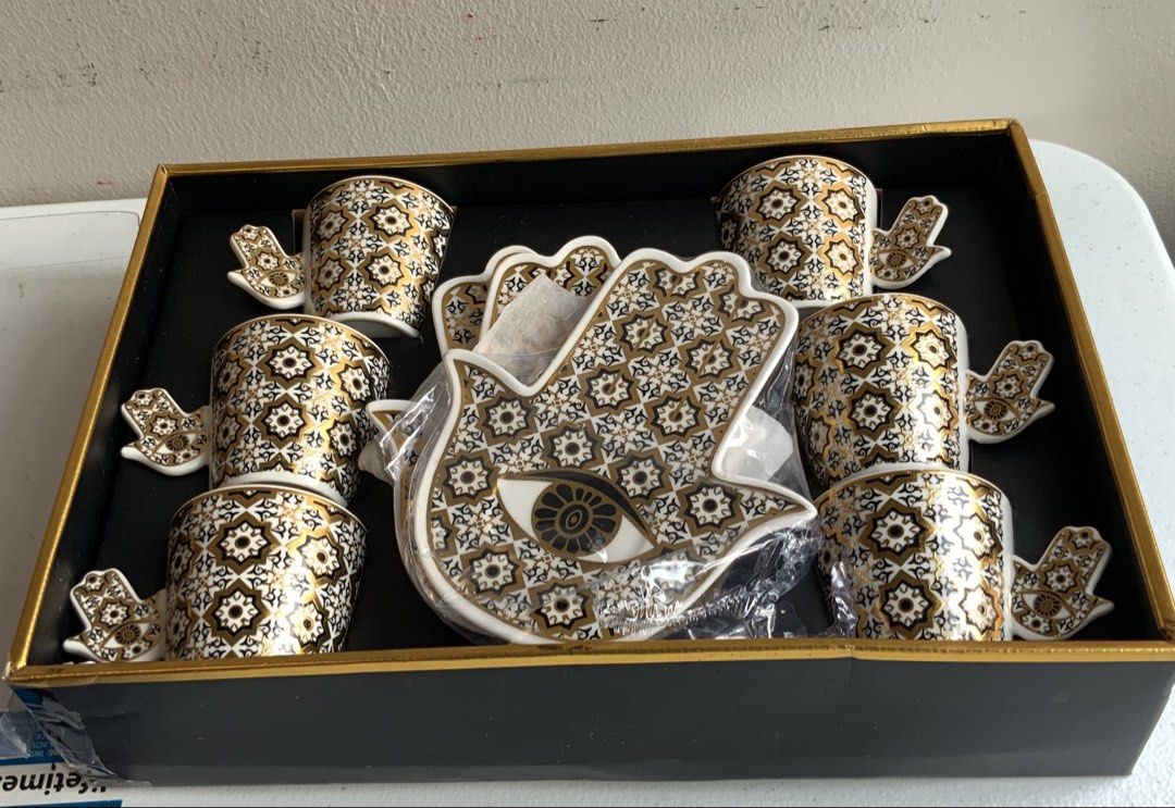 Hamsa Hand Evil Eye Coffee Cup and Saucer Set (Category: Coffee & Tea Tableware) located in Makati City. Submitted by nfb1234 (Listing ID 1450347256, Image 3). Description: - Set of 6 coffee cups and saucers - Features a Hamsa hand design with an evil eye in the center - Detailed gold and black pattern on cups and saucers - Comes in a beautiful presentation box - Ideal for serving espresso or Turkish coffee RFS - declutter .