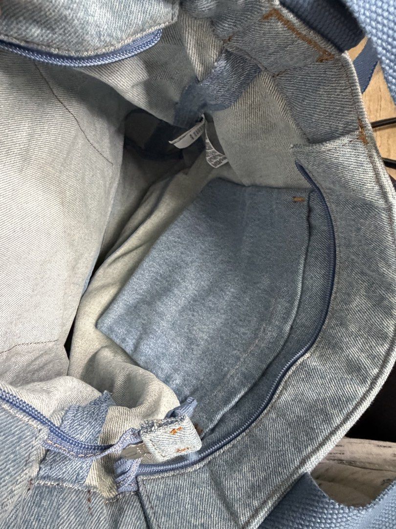 Levi's Denim Tote Bag with Pocket (Category: Tote Bags) located in Mandaluyong City. Submitted by PRETTYMNL_05 (Listing ID 1450332063, Image 3). Description: - Classic light wash denim tote bag by Levi's - Front pocket with embroidered Levi's logo - Interior zippered compartment for secure storage - Sturdy blue canvas straps for comfortable carrying - Ideal for everyday use, books, or groceries - Simple, functional, and stylish design.