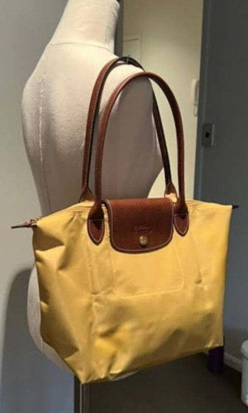 Longchamp Pliage. Original large Shoulder Tote Bag - Yellow (Category: Luxury Bags & Wallets) located in Navotas City. Submitted by riyuwi (Listing ID 1450509231, Image 2). Description: PreOwned Lightly Used Authentic Classic yellow Longchamp Pliage Original. Large Shoulder tote bag -long handle. Strap - Genuine leather handles and trim - Secure Ykk zipper closure with snap button flap (ORIGINAL .PRYM wth Hard jelly tag intact inside - Large, spa