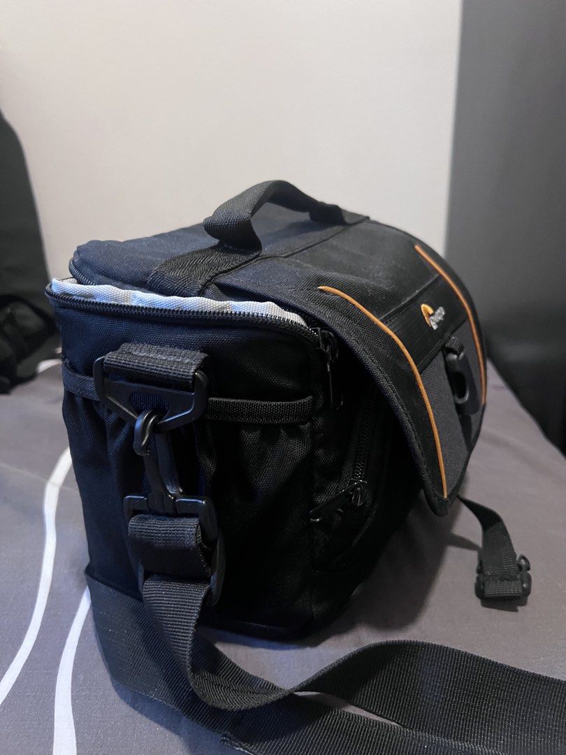 Lowepro Camera Bag (Category: Camera Bags & Carriers) located in Makati City. Submitted by bonjamora (Listing ID 1450368626, Image 2). Description: - Brand: Lowepro - Color: Black with orange trim - Interior: Adjustable dividers for camera and lenses - Features: Small zippered pocket inside lid - Includes: Shoulder strap - Benefit: Excellent protection for your camera gear.