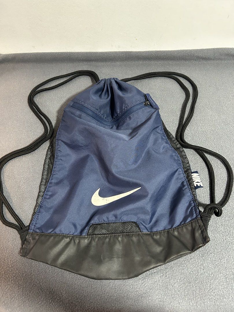 Nike Navy Blue Drawstring Bag with Zipper Pocket (Category: Backpacks) located in Baguio. Submitted by tristanzachary (Listing ID 1450519183, Image 3). Description: - Navy blue Nike drawstring bag - Front zipper pocket for extra storage - Mesh panels on the sides - Black faux leather bottom - Ideal for gym or everyday use - Drawstrings are in good working condition.