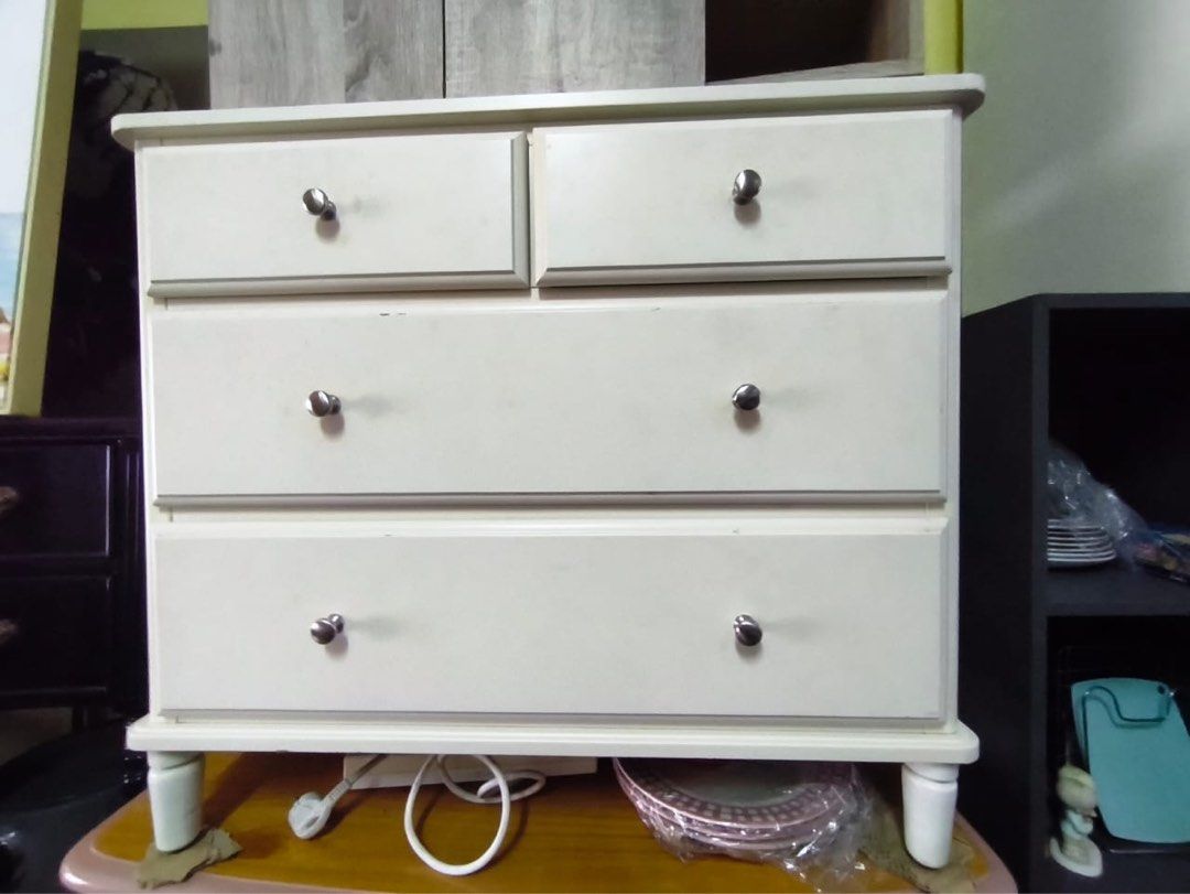 White 4-Drawer Dresser with Silver Knobs (Category: Shelves, Cabinets & Racks) located in Kuala Lumpur. Submitted by lazada.kim.huat.furniture (Listing ID 1450474703, Image 1). Description: - White dresser with a clean, simple design. - Features four drawers: two smaller top drawers and two larger bottom drawers. - Each drawer is fitted with a silver knob. - Stands on four short legs. - Minor scuffs visible on the surface, adding character. - Ide