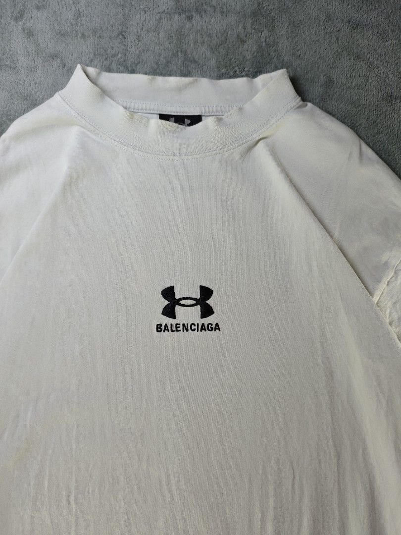 Balenciaga x Under Armour Collab White Oversized Tee (Category: Shirts) located in San Pedro. Submitted by chronothrift2ndacc (Listing ID 1450578067, Image 2). Description: - Size: XL (W23" x 30"L) - Condition: 9/10 - Color Rate: 9/10 - Flaws: Minimal Bacon Neck - Full Embroidery Design MOD: J&T Express / Lalamove / Meet MOP: Gcash / Bank Transfer.