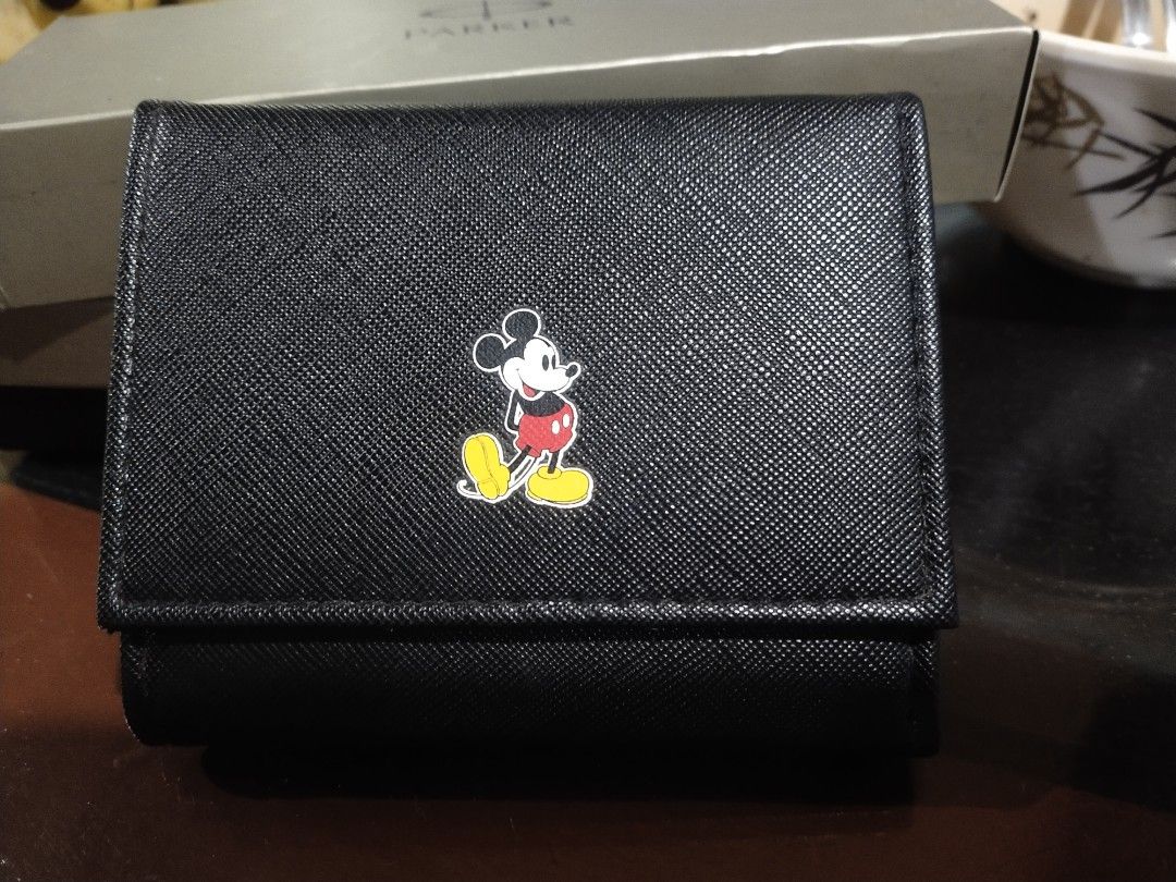 Black Tri-fold Wallet with Mickey Mouse Emblem (Category: Wallets & Card holders) located in Tuba. Submitted by drickbernard (Listing ID 1450528429, Image 2). Description: - Cute black tri-fold wallet - Classic Mickey Mouse emblem on the front - Multiple card slots inside - Coin compartment with snap closure - Small and compact for easy carrying - Ideal for Disney enthusiasts.