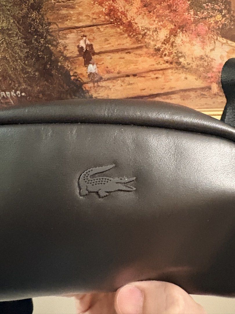 Lacoste Black Leather Crossbody Bag (Category: Cross-body Bags) located in Makati City. Submitted by goodbuyitems (Listing ID 1450654514, Image 3). Description: condition 9/10 decluttering. no issue. seldom used mini size. dimension 10 x 10 x 10 millimetres Black leather crossbody bag from Lacoste. Small and compact, great for essentials. Zipper closure. Adjustable strap. The logo is embossed on the front. Interior tag shows brand details..