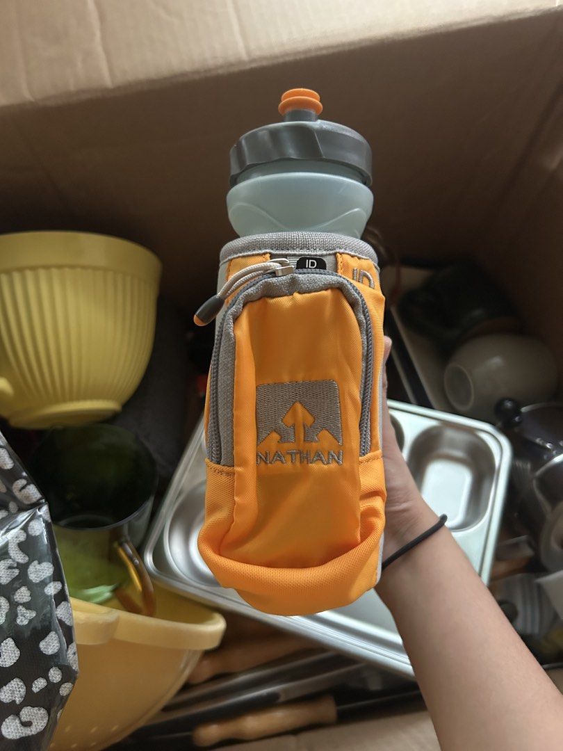 Nathan Orange Water Bottle Holder with Pouch (Category: Water Bottles & Tumblers) located in Manila. Submitted by keyscaninet (Listing ID 1450605856, Image 1). Description: - Nathan brand water bottle holder - Bright orange color with grey pouch - Mini backpack design with straps for easy carrying - Zippered pocket on the pouch for essentials - Ideal for running, hiking, and outdoor activities - Keeps your water bottle secure and your belongings 