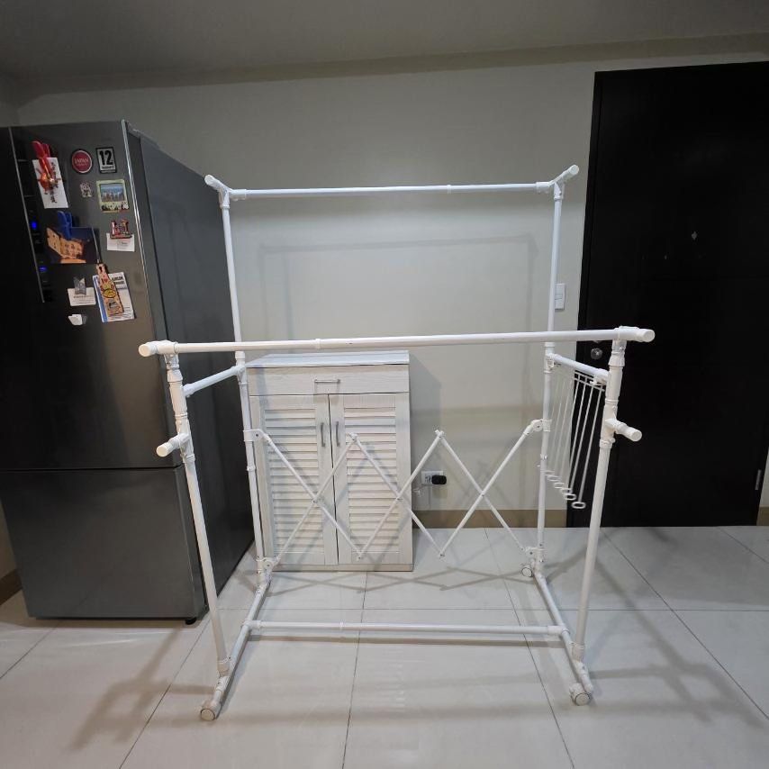 Nitori Extendable Drying Rack with FREE Hanging Shelves (Category: Shelves, Cabinets & Racks) located in Quezon City. Submitted by stylesaverph (Listing ID 1450572321, Image 3). Description: - White metal drying rack - Includes two hanging shelves with a striped pattern - Ideal for laundry or organizing clothes - Equipped with wheels for easy mobility - Sturdy and durable construction - Ready for its new owner- - we will Dismantle when delivered 