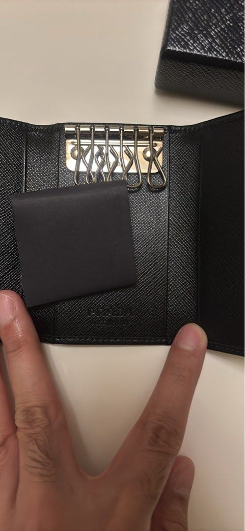 Prada Saffiano Leather 6 Key Holder Nero (Category: Luxury Bags & Wallets) located in Makati City. Submitted by ed_______ (Listing ID 1450684817, Image 3). Description: - Authentic Prada Key Holder - Material: Black Saffiano Leather - Includes: Original Box, Authenticity Card, Dust Pouch - Features: 6 Key Hooks - Origin: Made in Italy - Perfect for organizing your keys in style..