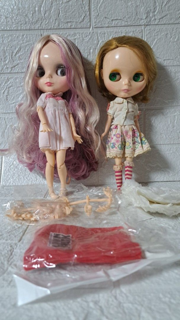 2x Blythe Dolls with Accessories - Hasbro 2006 (Category: Kids Toys) located in Quezon City. Submitted by hersheejubilo (Listing ID 1447232139, Image 1). Description: - Two authentic Hasbro Blythe dolls from 2006. - One doll features blonde hair and a floral dress. - The second doll has long purple and blonde hair and a white dress. - Comes with extra doll parts for customization. - Includes a stylish red bag. - Perfect for Blythe doll collectors