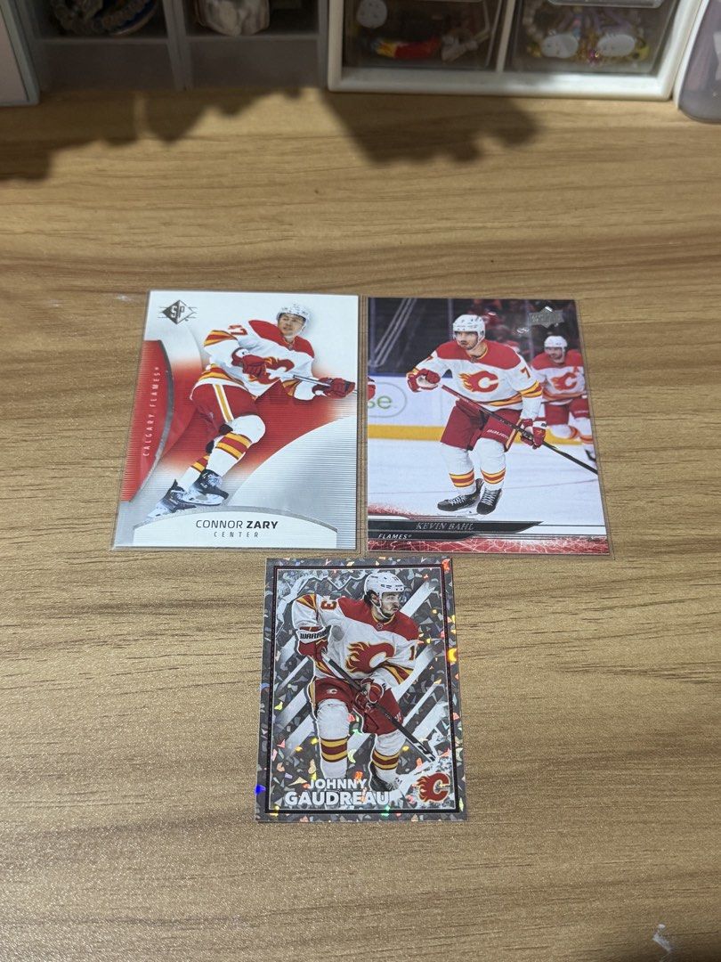 🏒 NHL Cards & Sticker: Calgary Flames set! (Category: Raw Singles) located in Taguig. Submitted by rayechord (Listing ID 1447212603, Image 2). Description: yes, i use the sylvanian cat for size reference 😊💐 🦭 team, players and card/sticker types: - Calgary Flames: Connor Zary 2025-26 SP #58 - Calgary Flames: Kevin Bahl 2024-25 Upper Deck Extended Series #518 - (then) Calgary Flames: ✝️ Johnny Gaudreau 2022-23 NHL Topps Sticker Album #72 - my 