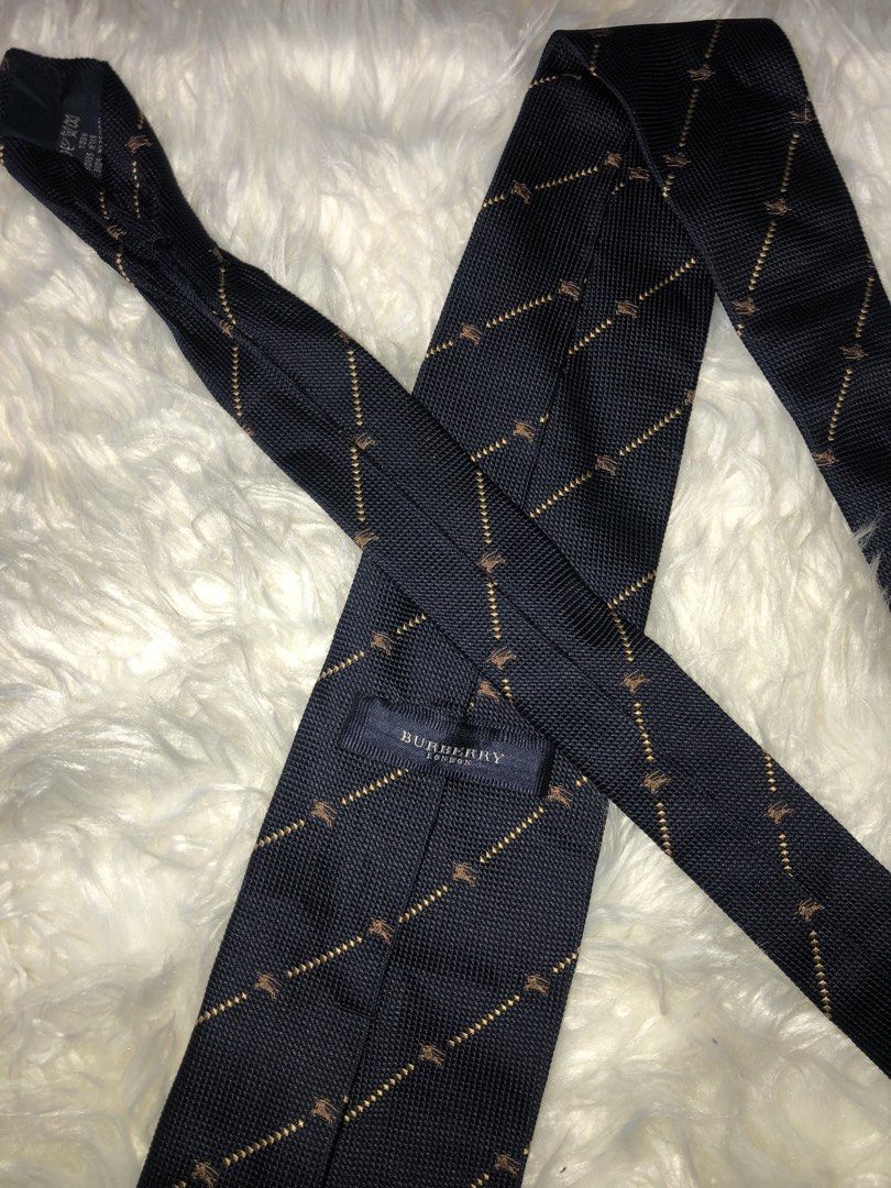 Burberry Neck Tie (Category: Luxury Accessories) located in Panay. Submitted by lumang__gamit00 (Listing ID 1447247685, Image 3). Description: This Burberry London silk tie features a navy base with a subtle diagonal pattern. Material: 100% Silk. Design: Diagonal gold lines with a small repeating pattern. Origin: Made in Italy..