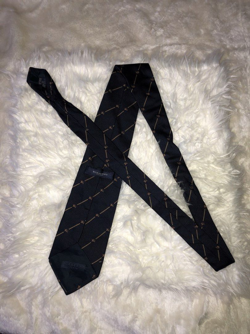 Burberry Neck Tie (Category: Luxury Accessories) located in Panay. Submitted by lumang__gamit00 (Listing ID 1447247685, Image 2). Description: This Burberry London silk tie features a navy base with a subtle diagonal pattern. Material: 100% Silk. Design: Diagonal gold lines with a small repeating pattern. Origin: Made in Italy..