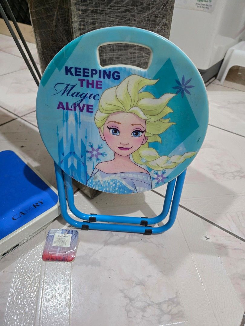 Disney Frozen Elsa Kids Stool (Category: Kids Tables & Chairs) located in Makati City. Submitted by shopaholicsgallery (Listing ID 1447228846, Image 2). Description: - Adorable stool featuring Elsa from Frozen - 'Keeping the Magic Alive' text - Sturdy blue metal legs - Convenient handle for easy carrying - Ideal for kids to sit on or use as a small table - Perfect for playtime or decorating their room - brand new, never used - RFS: decluttering.