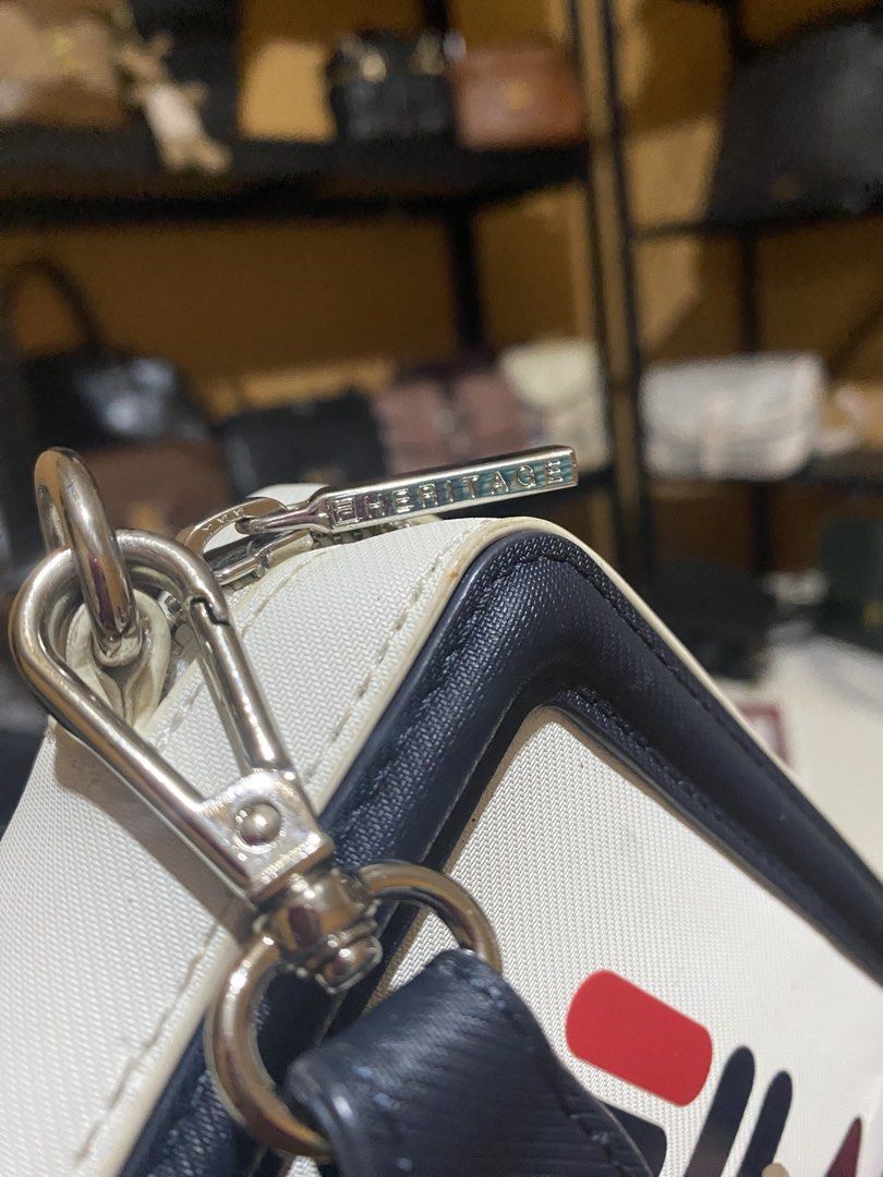 Fila Crossbody Bag White Navy Red Strap (Category: Cross-body Bags) located in Cavite. Submitted by rmquin05 (Listing ID 1447141393, Image 3). Description: - White crossbody bag with navy trim - Prominent Fila logo on the front - Detachable navy strap with Fila branding - Includes an additional red accent strap - Secure zipper closure - Small Fila logo detail on the zipper pull.