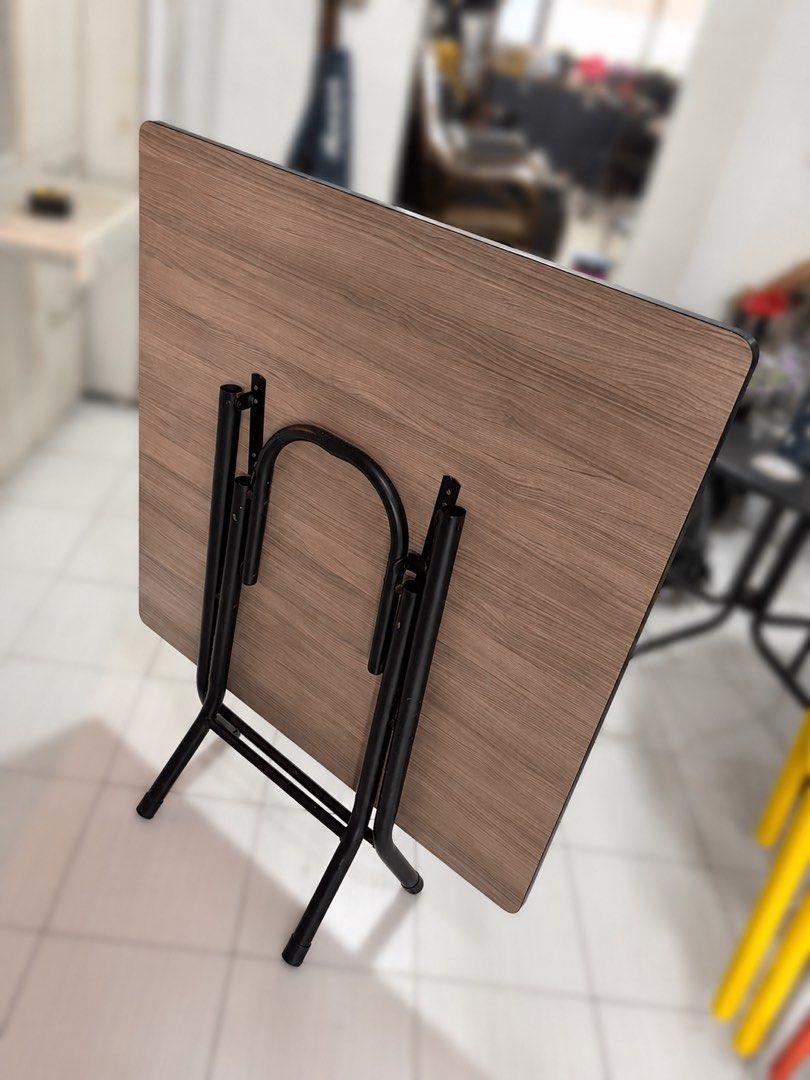 Foldable table (Category: Tables & Sets) located in Singapore. Submitted by vincent_shoshin (Listing ID 1447120277, Image 2). Description: - 90 * 90 * 73cm - Dark wood folding table - Wood grain finish top - Black metal legs fold for easy storage - Ideal for extra dining space or work - Sturdy and practical.