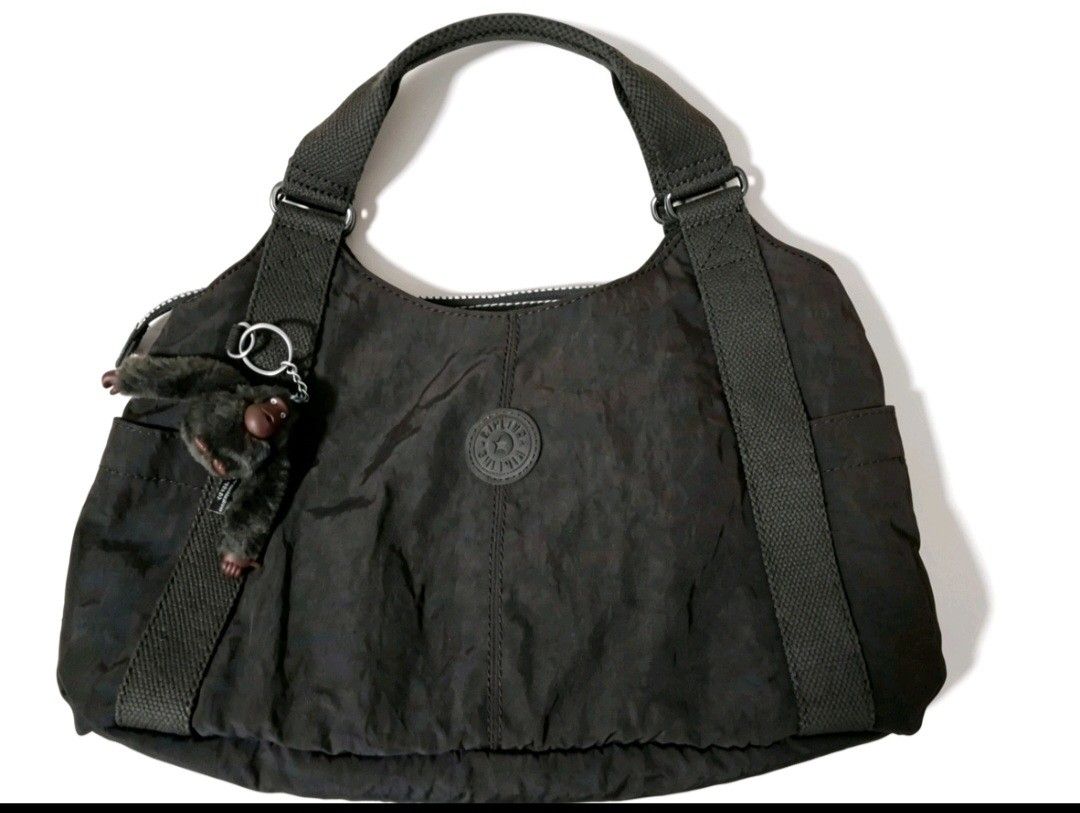 Kipling Dark Brown Nylon hand bag with Monkey Charm (Category: Shoulder Bags) located in Angeles City. Submitted by anneps (Listing ID 1447222192, Image 1). Description: - Dark brown Kipling hand bag - Made from durable nylon material - Secure zip closure - Multiple interior pockets for organization - Includes the signature Kipling monkey charm - Spacious design, ideal for everyday use.