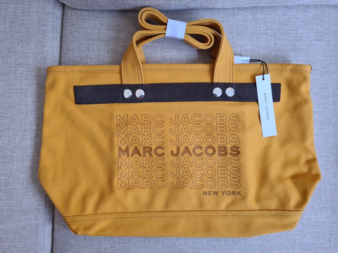 Marc Jacobs Yellow Canvas Tote Bag (Category: Luxury Bags & Wallets) located in Manila. Submitted by emskyeclaire (Listing ID 1447264486, Image 1). Description: - Authentic Marc Jacobs yellow canvas tote bag - Features repeated brand name and 'New York' print on the front - Comes with comfortable top handles - Includes a detachable shoulder strap for versatile carrying - Ideal for everyday use - Brand new with tags attached.