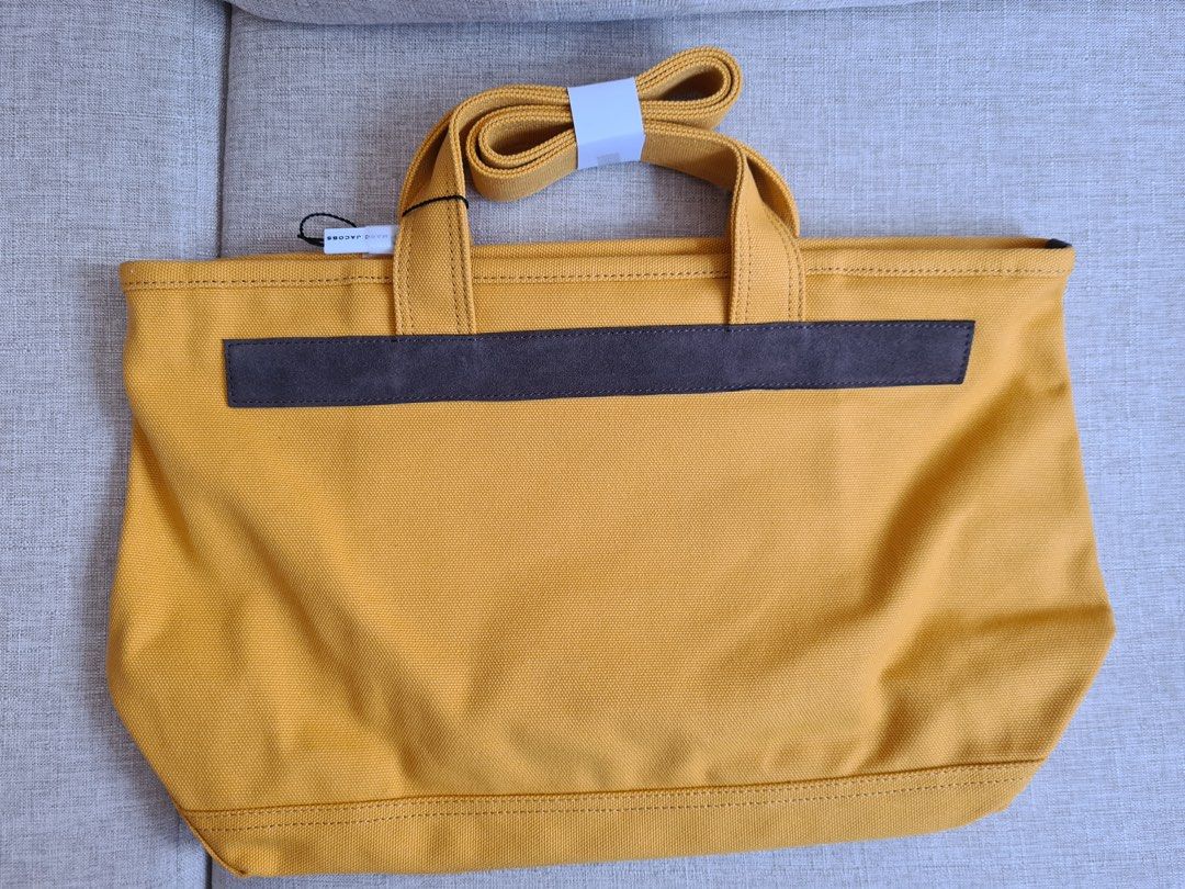 Marc Jacobs Yellow Canvas Tote Bag (Category: Luxury Bags & Wallets) located in Manila. Submitted by emskyeclaire (Listing ID 1447264486, Image 2). Description: - Authentic Marc Jacobs yellow canvas tote bag - Features repeated brand name and 'New York' print on the front - Comes with comfortable top handles - Includes a detachable shoulder strap for versatile carrying - Ideal for everyday use - Brand new with tags attached.