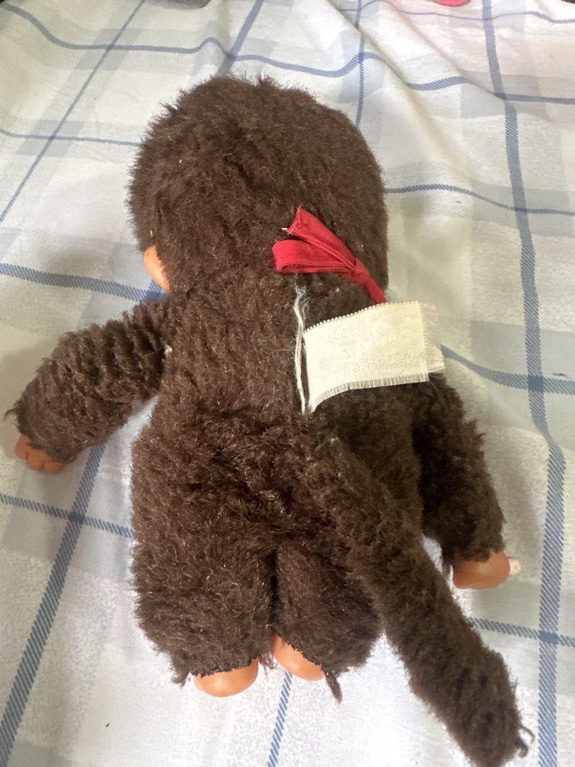Monchhichi Monkey Plush Toy with Bib and Red Bow (Category: Plushies & Soft Toys) located in Cainta. Submitted by shopbyyna (Listing ID 1447134025, Image 2). Description: - Adorable Monchhichi monkey plush toy. - Features original 'Monchhichi' bib. - Cute red bow on head and red ribbon at the back. - Soft, fluffy brown fur. - Hands and feet made of soft plastic. - Includes a tail. As is from japan auction bale.
