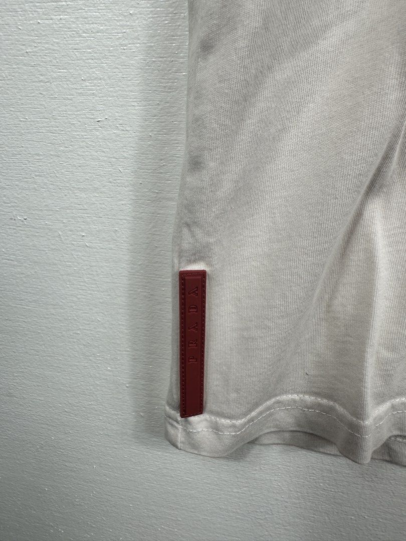 Prada White Pocket T-Shirt XL (Category: Tshirts & Polo Shirts ) located in Manila. Submitted by collect__ph (Listing ID 1447131987, Image 3). Description: - Authentic Prada Pocket Tee - Size: 26.5” L x 22” W - Signature red Prada tab on the side - Material: 100% Cotton - Care: Wash cold, inside out, separately. Do not soak/wring. Iron on dry clean setting..