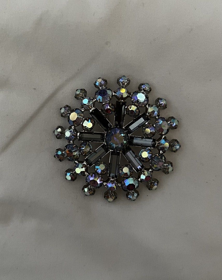 Sparkling Starburst Brooch with Rhinestones (Category: Brooches) located in Tabuk. Submitted by zenwolf-1867 (Listing ID 1447262911, Image 2). Description: - Stunning starburst design brooch - Adorned with clear and iridescent rhinestones - Dark gunmetal grey metal finish - Secure pin closure on the back - Arrives in a beautiful gift box - Ideal accessory for jackets, scarves, and more.