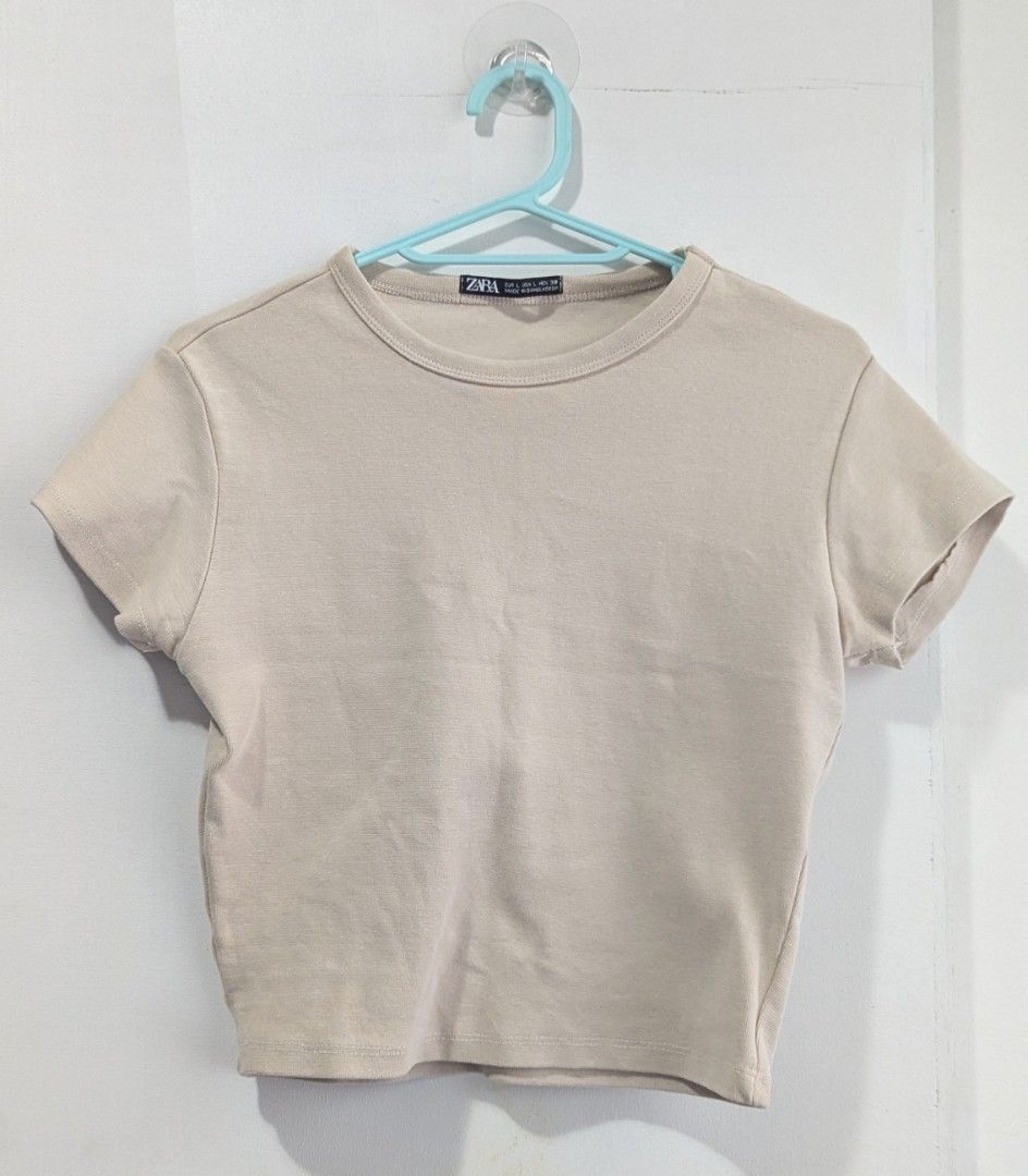 Zara Beige Cropped T-Shirt (Category: Shirts) located in Marikina City. Submitted by mlektea (Listing ID 1447170991, Image 1). Description: Thick fabric, basic crop top in Beige - Brand: Zara - Color: Beige - Style: Cropped T-shirt - Neckline: Crew neck - Sleeves: Short sleeves - Measurements: 15 inches wide, 17 inches long - Condition: Gently used (implied) - Versatility: Great for layering or wearing solo.