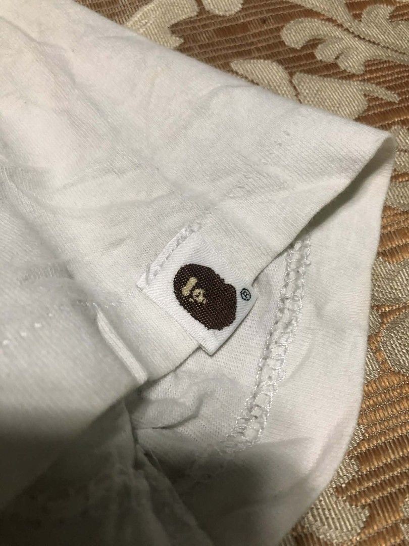 BAPE AAPE By A Bathing Ape T-Shirt (Category: Tshirts & Polo Shirts ) located in Manila. Submitted by rai_0413 (Listing ID 1450888955, Image 2). Description: - Brand: BAPE - Color: White - Size: S - Material: 100% Cotton - Style: Casual wear - Condition: Good - Features: Classic ape graphic with intricate details 19x23 need wash oil stain sign of usage neck 8.5 CR.