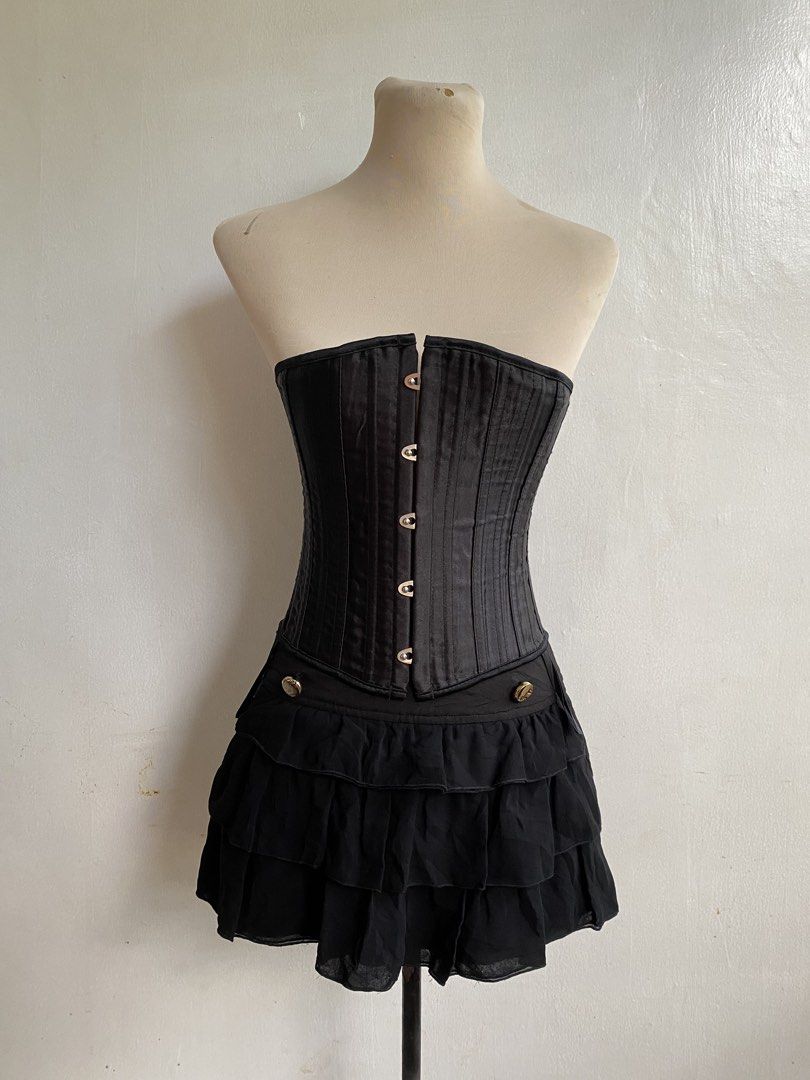 Black Corset with Bones (Category: Sets or Coordinates) located in Tumauini. Submitted by bihisbyme (Listing ID 1450880516, Image 1). Description: - Black corset with front clasps and lace-up back - Satin-like finish with vertical stitching - Attached short, ruffled black skirt - Decorative buttons on skirt - Adjustable fit for a custom look - Ideal for costumes or a bold fashion statement Issue: please check photo Overall, still useful. .