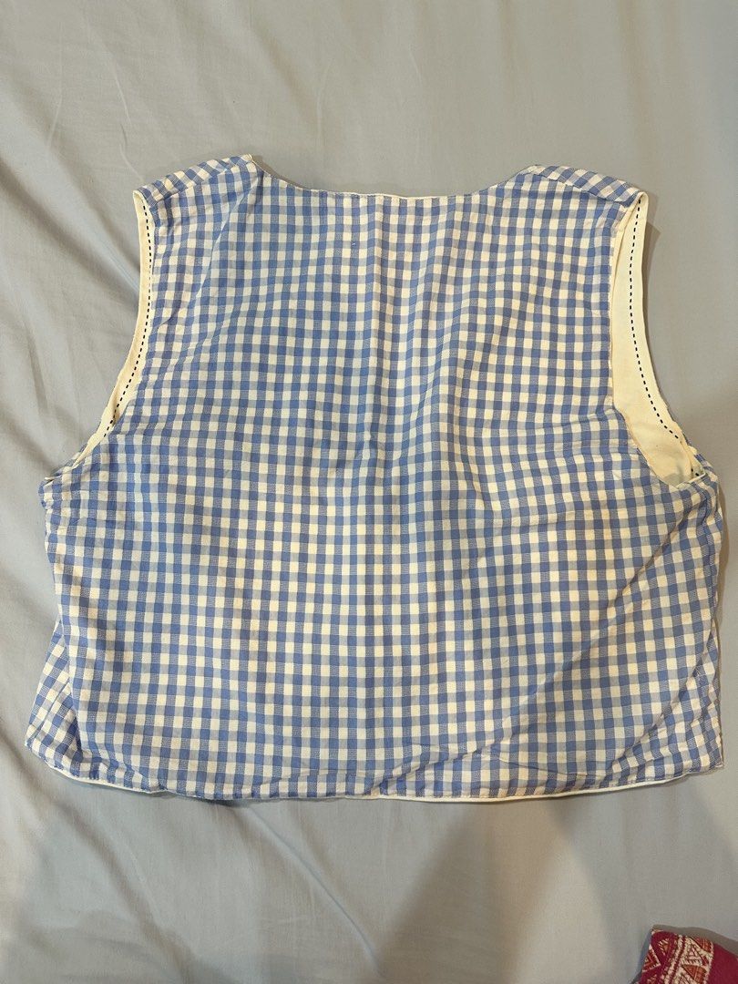 Cider Gingham Reversible Vest (Category: Sleeveless) located in Paranaque City. Submitted by applemt (Listing ID 1450868947, Image 2). Description: - One side: Blue gingham - Other side: White with mermaid, shell, and flower appliques - Ties at the front - Size Large, tag removed as it’s scratching my back - Armpit to armpit laid flat: 19”.