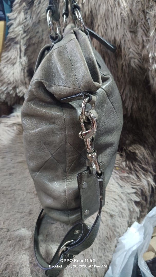 Coach Leather Satchel Bag Grey Quilted (Category: Luxury Bags & Wallets) located in Manila. Submitted by wildwind_49ab7e (Listing ID 1450771952, Image 3). Description: - Genuine grey leather Coach satchel bag - Secure turn-lock closure on front pocket - Spacious interior with multiple compartments - Includes a detachable shoulder strap for versatile carrying - Leather shows some signs of wear, particularly on the base - Ideal for everyday use.