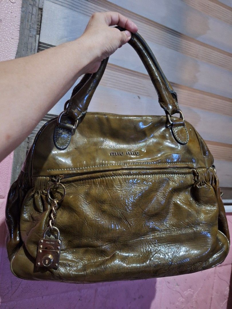 Miu Miu Patent Leather Handbag (Category: Luxury Bags & Wallets) located in Quezon City. Submitted by cloudymay (Listing ID 1450872247, Image 2). Description: - Glossy olive green Miu Miu handbag - Prominent Miu Miu logo - Secure magnetic closure - Unique lock detail with chain - Crinkled patent leather finish - Sturdy handles attached with buckles - Ideal for stylish everyday use * Accesories not included. Its just a suggestion as to how I style