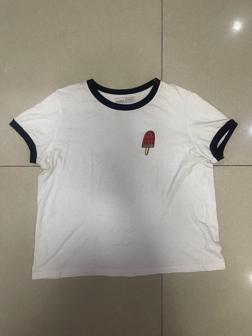Pull & Bear White T-shirt with Popsicle Graphic (Category: Tshirts & Polo Shirts ) located in Manila. Submitted by offtherack_mnl (Listing ID 1450893692, Image 1). Description: - White ringer tee from Pull & Bear - Features a cute popsicle graphic on the chest - Black trim on collar and sleeves - Perfect for a casual look.