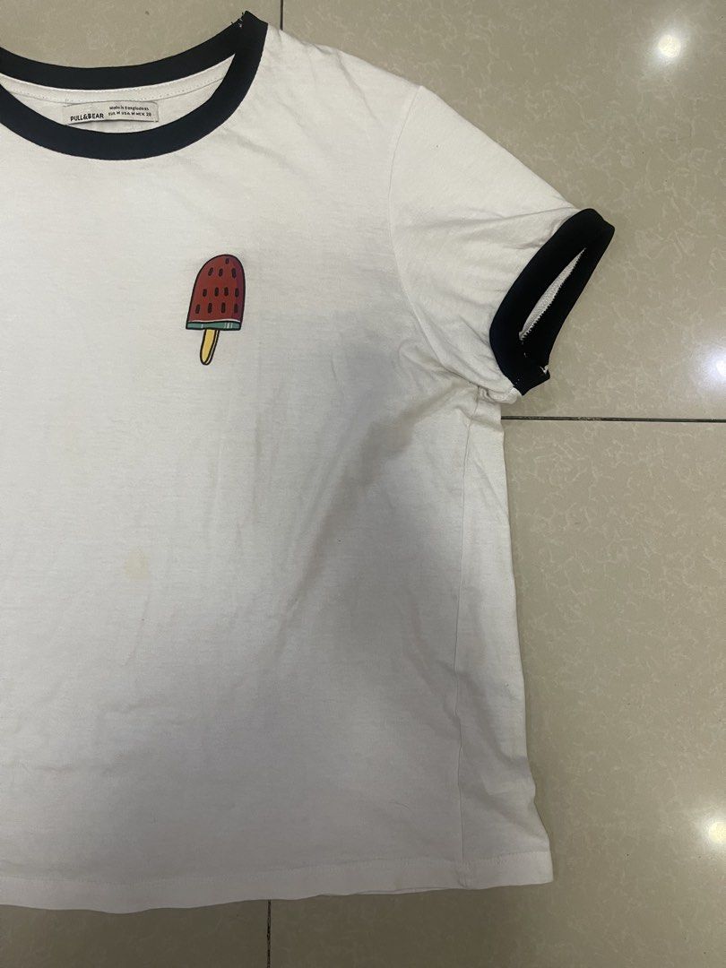 Pull & Bear White T-shirt with Popsicle Graphic (Category: Tshirts & Polo Shirts ) located in Manila. Submitted by offtherack_mnl (Listing ID 1450893692, Image 2). Description: - White ringer tee from Pull & Bear - Features a cute popsicle graphic on the chest - Black trim on collar and sleeves - Perfect for a casual look.