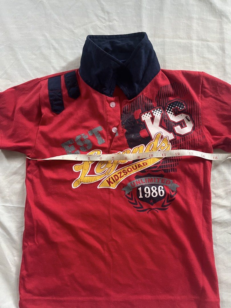 Red KidzSquad Polo Shirt (Category: Shirts) located in Pamplona. Submitted by vjbordon (Listing ID 1450846391, Image 2). Description: - Red short-sleeved polo shirt for kids - Features a navy collar - 'Legends KidzSquad 1986' graphic print - Minor signs of wear on sleeve cuffs - Loose threads on shoulder strap can be sewn before shipping - Ideal for casual wear ✨Strictly payment first policy. ✨Buyer will shoulder the shipping fee. ✨No cancellatio