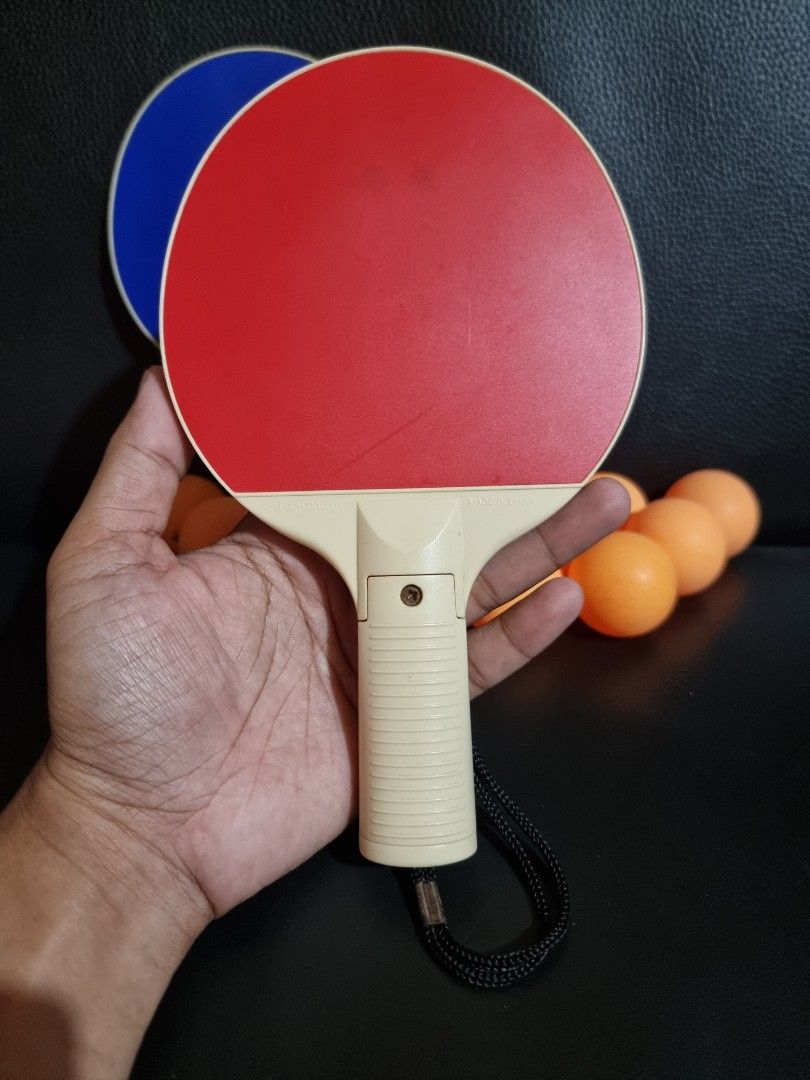 Table Tennis Paddles and 12 Balls Set (Category: Racket and Ball Sports) located in Imus. Submitted by aim_for_less (Listing ID 1450896159, Image 2). Description: - Set includes 2 table tennis paddles (1 red, 1 blue) - Comes with 12 standard-sized orange table tennis balls - Ideal for casual play and recreational fun - Paddles feature comfortable grips for better control - Includes wrist straps for added security during play.