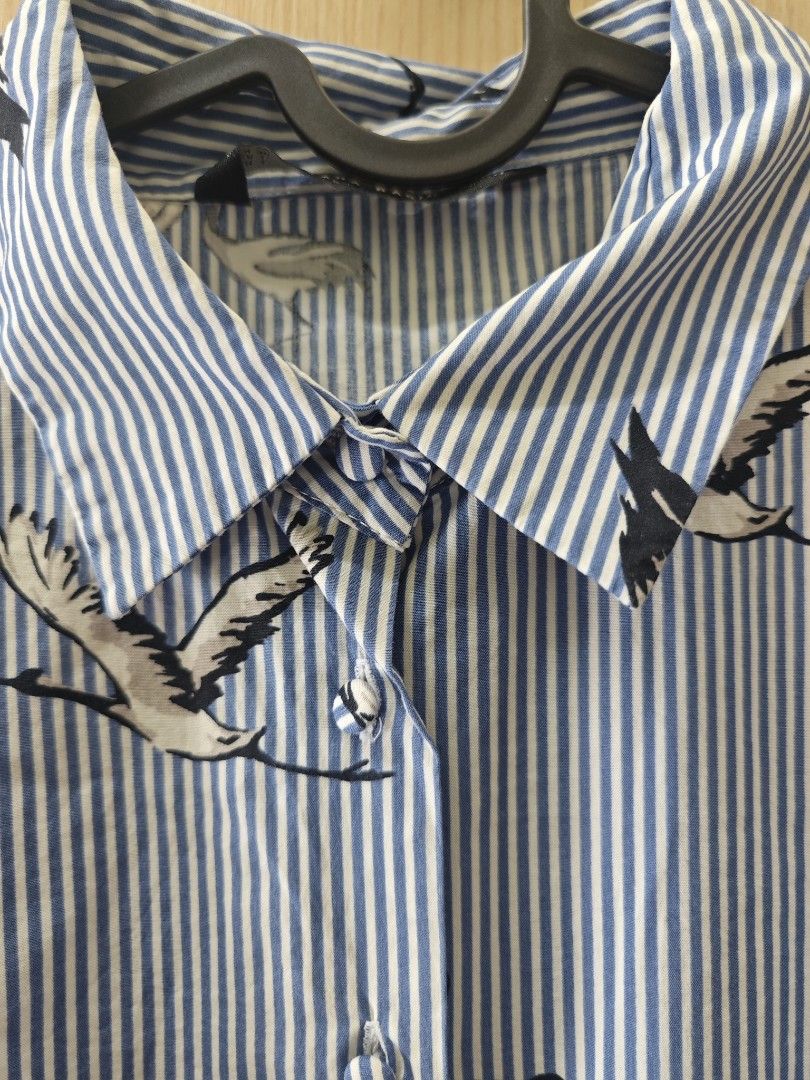ZARA BASIC COLLECTION Blue Striped Crane Print Shirt (Category: Shirts) located in Taguig. Submitted by hellojuly (Listing ID 1450796902, Image 2). Description: - Blue and white striped shirt - Features a stylish crane print - Short sleeves - Collared neckline - Button-up front - Elasticated hem for a comfortable fit - Size: Large (L) but can fit medium - From Zara Basic Collection - Made in Morocco - Perfect for casual outings.