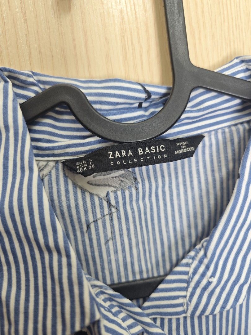 ZARA BASIC COLLECTION Blue Striped Crane Print Shirt (Category: Shirts) located in Taguig. Submitted by hellojuly (Listing ID 1450796902, Image 3). Description: - Blue and white striped shirt - Features a stylish crane print - Short sleeves - Collared neckline - Button-up front - Elasticated hem for a comfortable fit - Size: Large (L) but can fit medium - From Zara Basic Collection - Made in Morocco - Perfect for casual outings.
