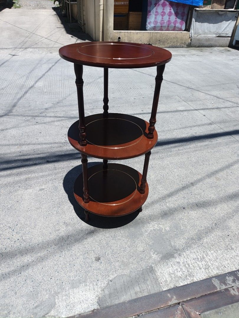 3-Tier Round Wooden Side Table (Category: Tables & Sets) located in Valenzuela. Submitted by kendra071914 (Listing ID 1450943385, Image 3). Description: - Three-tier round side table - Dark wood finish with lighter wood edge accents - Middle and bottom shelves are black - Stands approximately 76cm tall - Diameter of 38cm - Ideal for displaying plants or decorative items.