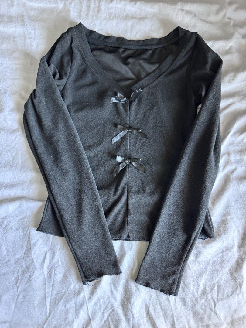 Grey Long Sleeve Top with Bow Details (Category: Longsleeves) located in Pasay City. Submitted by idaboutique (Listing ID 1451066018, Image 2). Description: - Grey long-sleeved top - Flattering V-neckline - Three small bow details down the front - Stretchy and soft material - Versatile for layering or wearing alone - Ideal for casual outfits.