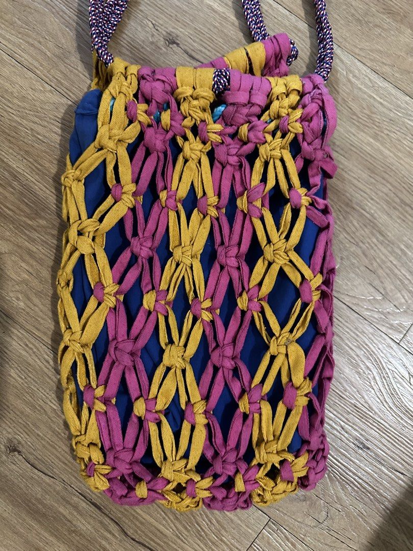Ola Haus Bag (Category: Cross-body Bags) located in Las Pinas. Submitted by petiteclothes_2000 (Listing ID 1451038859, Image 2). Description: - Handwoven bucket bag - Unique macrame-style outer layer in yellow and pink - Blue inner lining - Braided strap with purple and pink threads - Zipper closure - Ideal for everyday use.