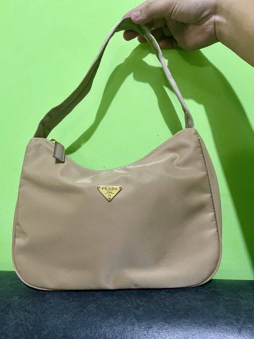 PRADA RE EDITION (Category: Luxury Bags & Wallets) located in Dagupan City. Submitted by casadebayongph (Listing ID 1451042402, Image 2). Description: - Prada shoulder bag - Beige nylon material - Gold hardware details - Zipper closure - Classic triangular Prada logo on front - Comfortable shoulder strap - Ideal for everyday use - Fits all your essentials.